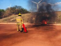 Pessoa com equipamento para combate a incêndio segurando extintor em ambiente aberto