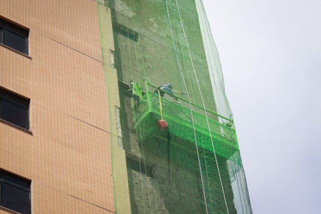 Colaborador da SELF Engenharia retirando acabamento antigo da fachada do Condomínio Lustosa da Câmara